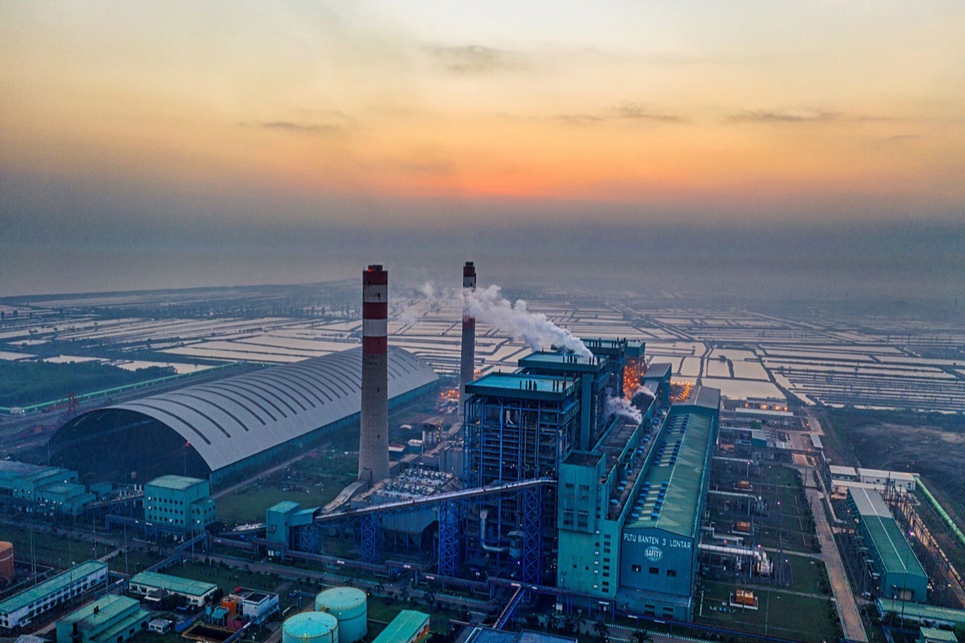 Aerial view of an industrial plant with smokestacks in Banten, Indonesia at sunrise.